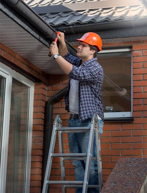 Man on ladder fixing gutters